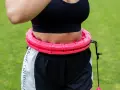 Kobieta ćwiczy z różowym hula hop. Czy hula hop jest szkodliwe? Ten model wydaje się bezpieczny i skuteczny.