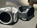 Dwa smartwatche, biały i szary, leżą obok siebie. Dowiedz się, jak namierzyć smartwatch, gdy zgubisz go w domu lub na spacerze.