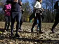 Grupa osób uprawia slow jogging w parku jesienią. Widać ich nogi i fragmenty ubrań. To świetne efekty dla zdrowia i samopoczucia.