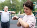 Kobieta sprawdza na zegarku dane treningowe, być może porównując je z tabelą długość kroku człowieka.
