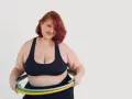 Kobieta z rudymi włosami i hula hop zastanawia się, ile trzeba kręcić hula hop żeby schudnąć.