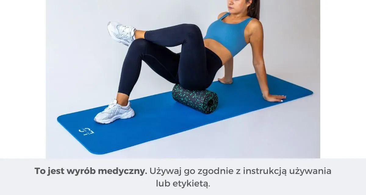 Kobieta wykonuje ćwiczenia na ból pośladków, używając rollera do masażu na macie.