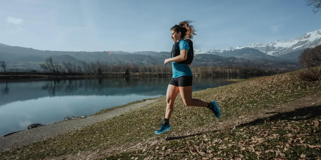Kobieta biegnie nad jeziorem, w tle góry. Czas na 10 km!