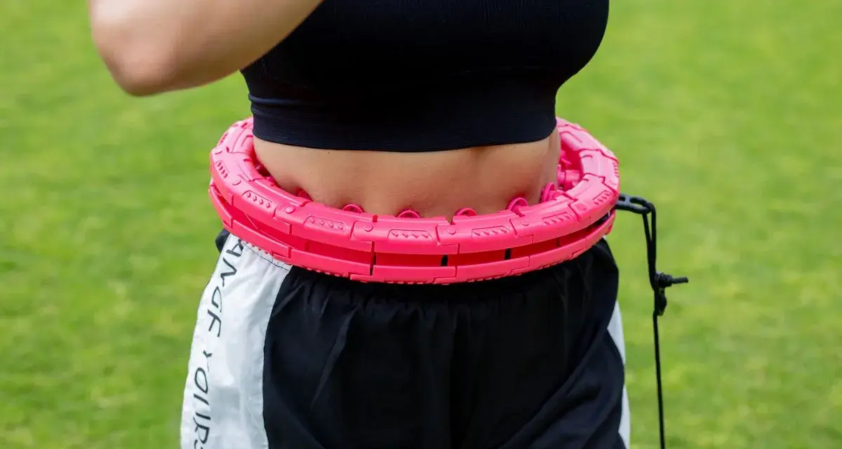 Kobieta ćwiczy z różowym hula hop. Czy hula hop jest szkodliwe? Ten model wydaje się bezpieczny i skuteczny.