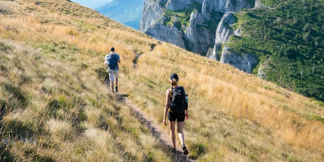 Dwie osoby wędrują po górskim szlaku. Zastanawiasz się, ile się idzie 1km w takich warunkach?