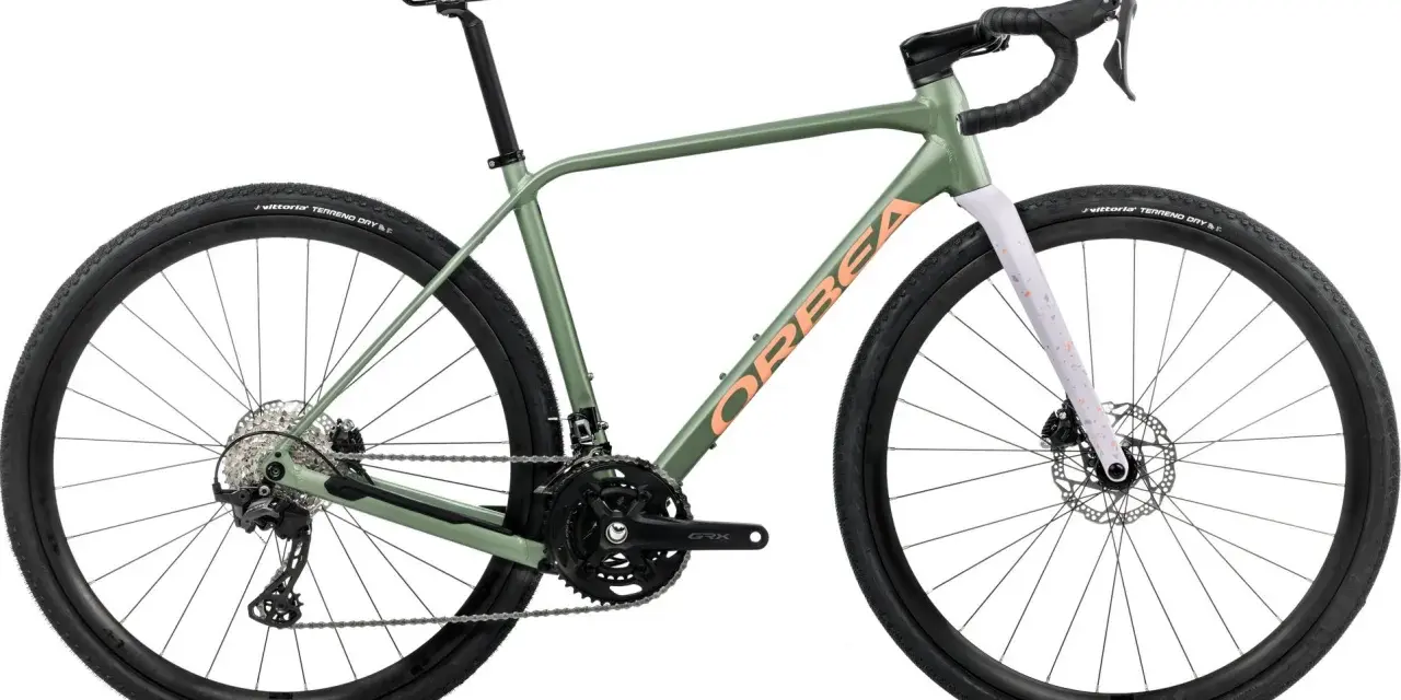 Zielony rower gravel Orbea z pomarańczowym napisem. Idealny na szutrowe trasy, bo gravel to wszechstronność.