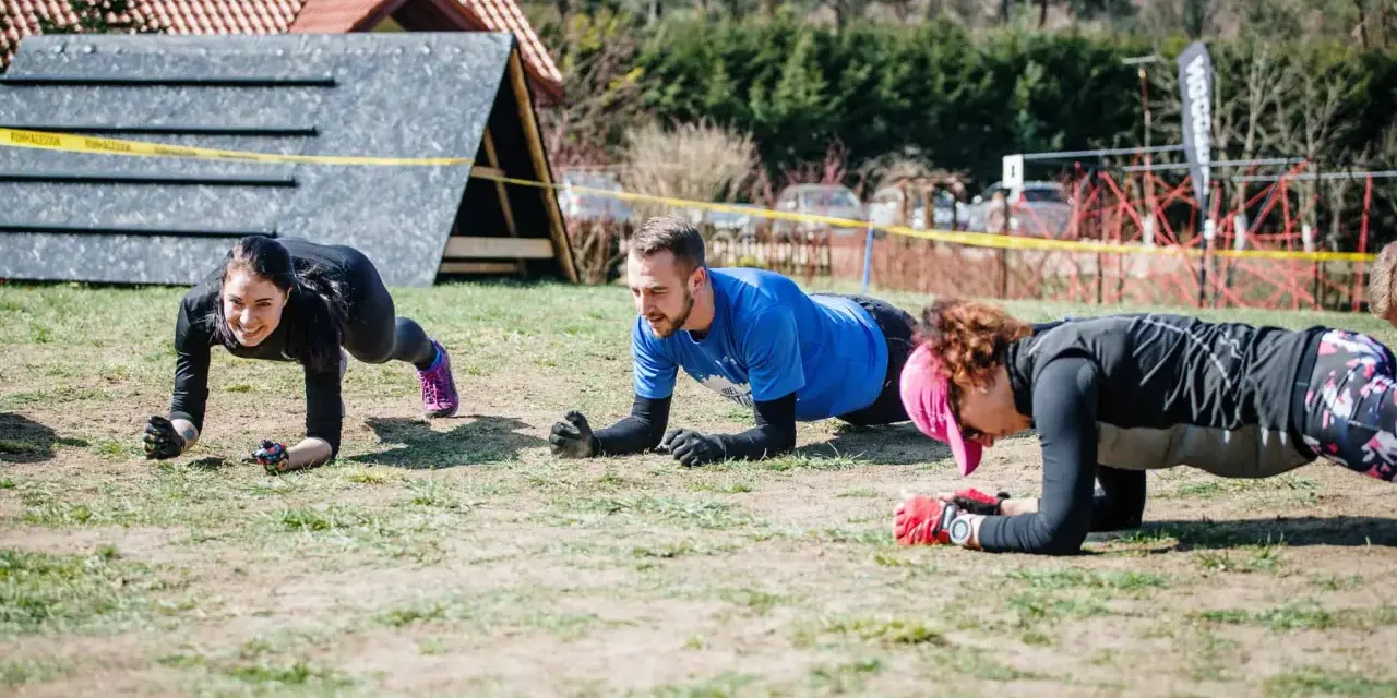 Trzy osoby ćwiczą w pozycji deski, przygotowując się do Runmageddonu.