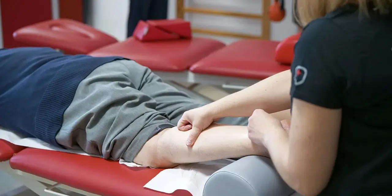 Fizjoterapeuta masuje nogę pacjenta, który doświadcza spadku formy.