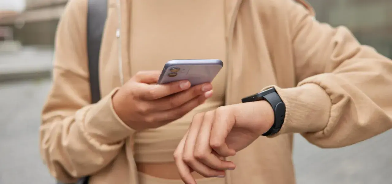 Osoba sprawdza na telefonie poziom stresu Garmin, nosząc smartwatch.