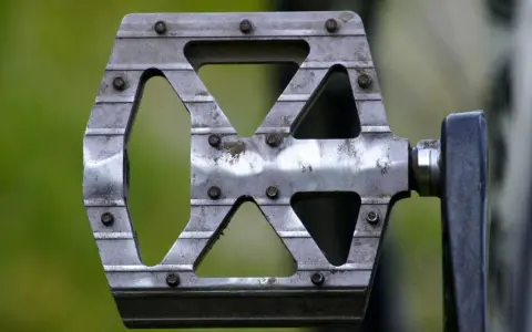 Metalowy pedał rowerowy z widocznymi śrubami. Dowiedz się, jak odkręcić pedały, by wymienić je lub wyczyścić.