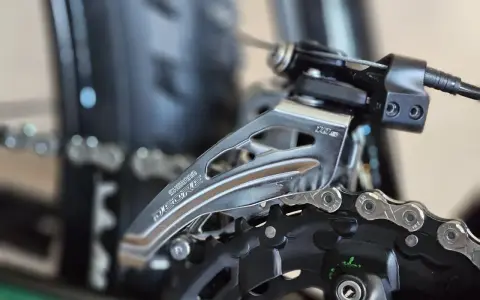 Precyzyjna regulacja przerzutek w rowerze Shimano Deore. Widoczny mechanizm przerzutki przedniej i fragment łańcucha.