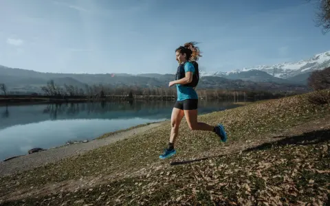 Kobieta biegnie nad jeziorem, w tle góry. Czas na 10 km!
