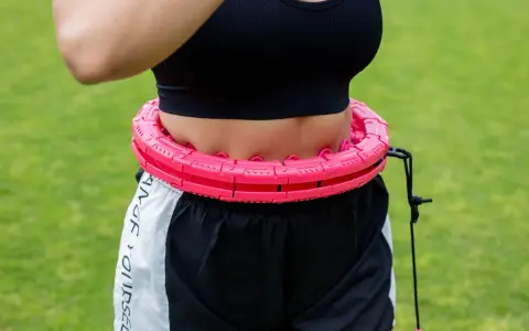 Kobieta ćwiczy z różowym hula hop. Czy hula hop jest szkodliwe? Ten model wydaje się bezpieczny i skuteczny.