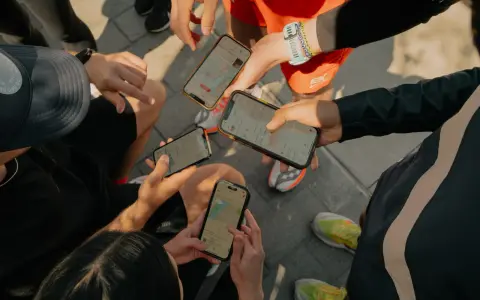 Grupa biegaczy analizuje swoje wyniki na telefonach. Widać mapy tras i statystyki aktywności, typowe dla aplikacji Strava po polsku.