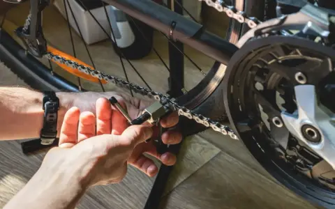 Instrukcja: jak założyć łańcuch w rowerze. Dłoń z narzędziem przykłada się do ogniw łańcucha, przygotowując go do montażu.
