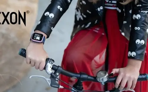 Dziecko w kurtce z oczkami trzyma kierownicę roweru. Na ręce ma różowy pasek do smartwatch dla dzieci.