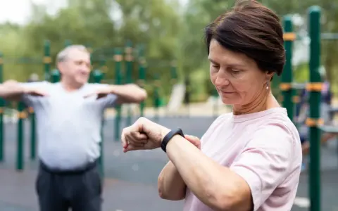 Kobieta sprawdza na zegarku dane treningowe, być może porównując je z tabelą długość kroku człowieka.