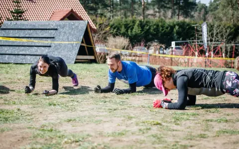 Trzy osoby ćwiczą w pozycji deski, przygotowując się do Runmageddonu.