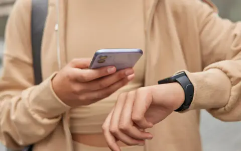 Osoba sprawdza na telefonie poziom stresu Garmin, nosząc smartwatch.