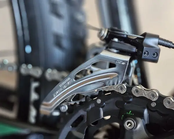 Precyzyjna regulacja przerzutek w rowerze Shimano Deore. Widoczny mechanizm przerzutki przedniej i fragment łańcucha.