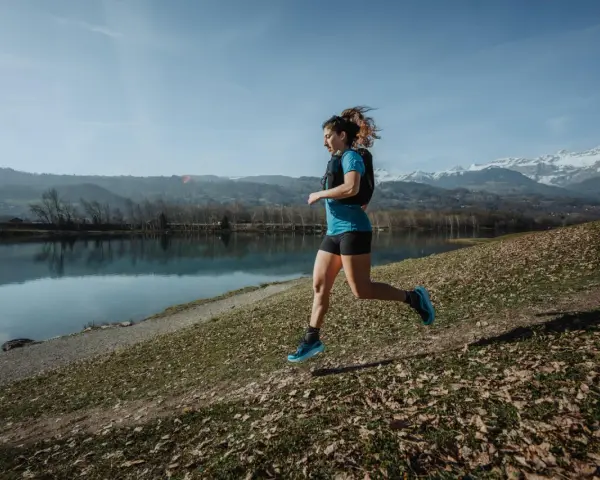 Kobieta biegnie nad jeziorem, w tle góry. Czas na 10 km!
