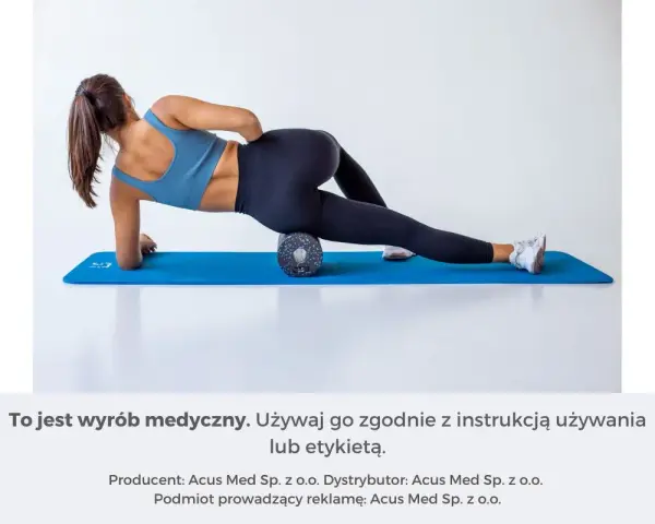 Kobieta wykonuje rolowanie mięśni uda na wałku do masażu, leżąc na macie.