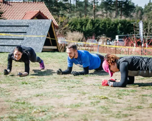 Trzy osoby ćwiczą w pozycji deski, przygotowując się do Runmageddonu.