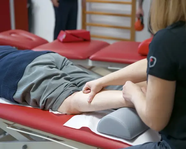Fizjoterapeuta masuje nogę pacjenta, który doświadcza spadku formy.