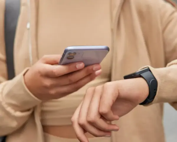 Osoba sprawdza na telefonie poziom stresu Garmin, nosząc smartwatch.