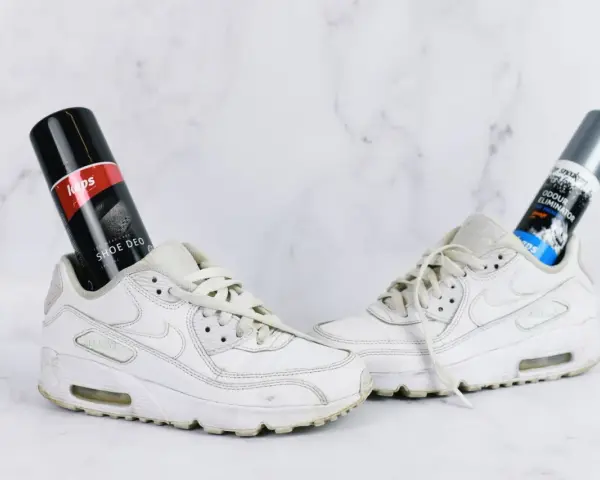 Białe sneakersy z włożonymi do środka dezodorantami do butów. Skuteczne domowe sposoby na śmierdzące buty.