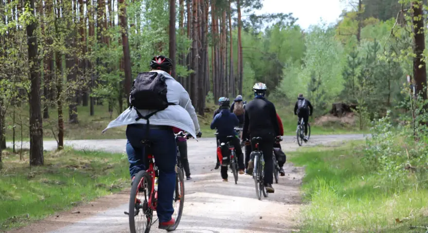 Grupa rowerzystów przemierza leśną ścieżkę. Każdy kilometr to spalony kcal, a widoki wynagradzają wysiłek.