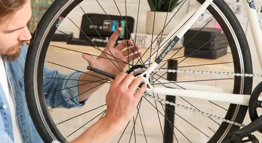 Mężczyzna używa narzędzia, by dowiedzieć się, jak odkręcić tylną zębatkę w rowerze.