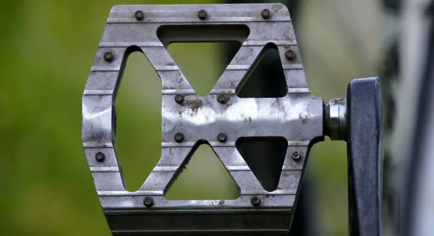 Metalowy pedał rowerowy z widocznymi śrubami. Dowiedz się, jak odkręcić pedały, by wymienić je lub wyczyścić.