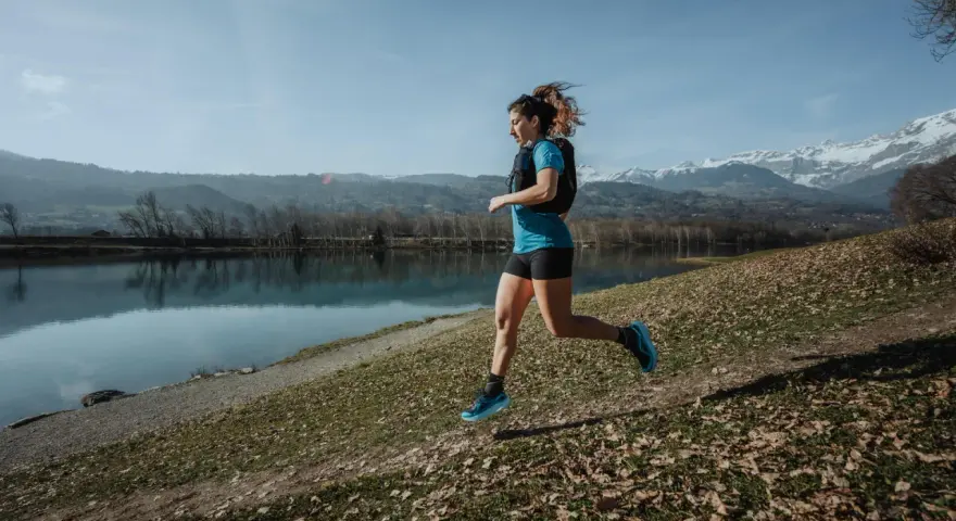 Kobieta biegnie nad jeziorem, w tle góry. Czas na 10 km!
