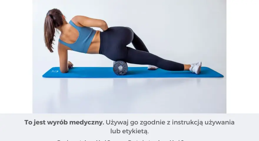 Kobieta wykonuje rolowanie mięśni uda na wałku do masażu, leżąc na macie.
