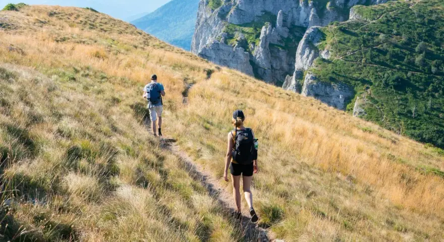 Dwie osoby wędrują po górskim szlaku. Zastanawiasz się, ile się idzie 1km w takich warunkach?