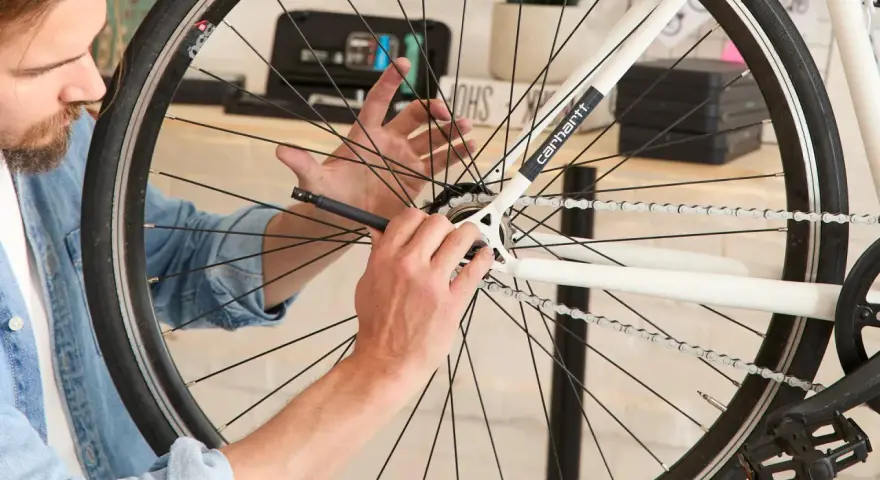 Mężczyzna dokonuje wymiany kasety w rowerze, używając specjalnego narzędzia do odkręcenia zębatki.