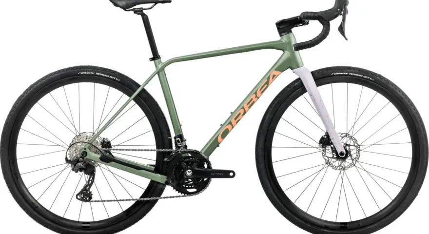 Zielony rower gravel Orbea z pomarańczowym napisem. Idealny na szutrowe trasy, bo gravel to wszechstronność.