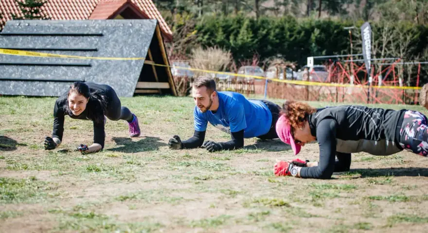 Trzy osoby ćwiczą w pozycji deski, przygotowując się do Runmageddonu.