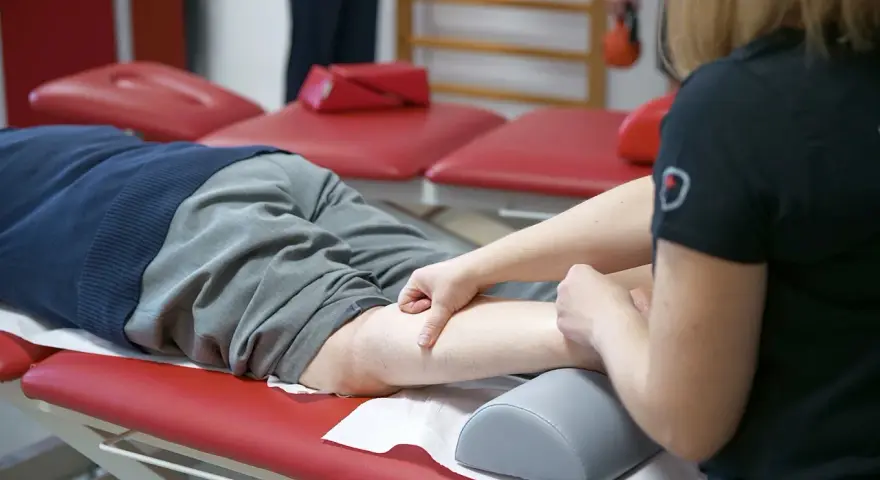 Fizjoterapeuta masuje nogę pacjenta, który doświadcza spadku formy.