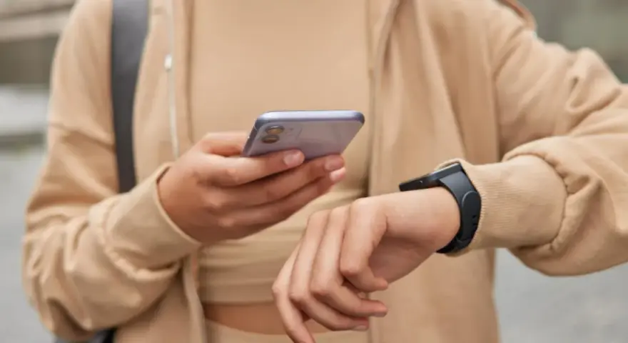Osoba sprawdza na telefonie poziom stresu Garmin, nosząc smartwatch.