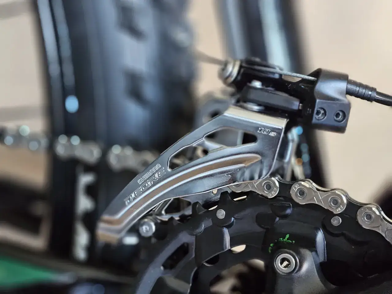 Precyzyjna regulacja przerzutek w rowerze Shimano Deore. Widoczny mechanizm przerzutki przedniej i fragment łańcucha.