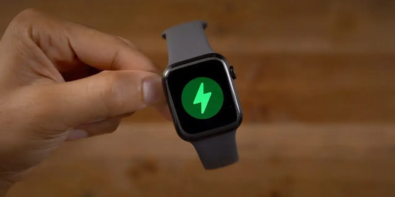 Dłoń trzyma smartwatch z ikoną ładowania. Dowiedz się, jak ładować smartwatch, aby zawsze był gotowy do działania.