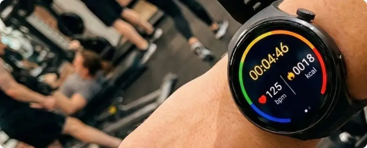 Zegarek fit pro na nadgarstku pokazuje 125 bpm i 18 kcal podczas treningu w tle.